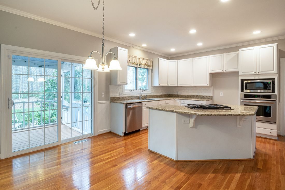 An empty kitchen with bare counters and polished hardwood floors