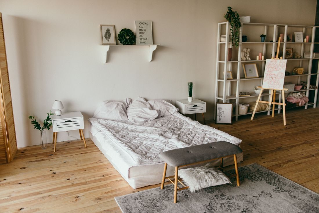 A neatly made bed in a bright guest bedroom with wood floors