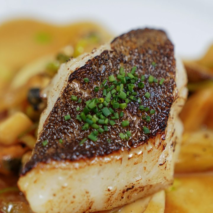 A fillet of wreckfish with a deeply seared crust and chives, in a golden butter sauce