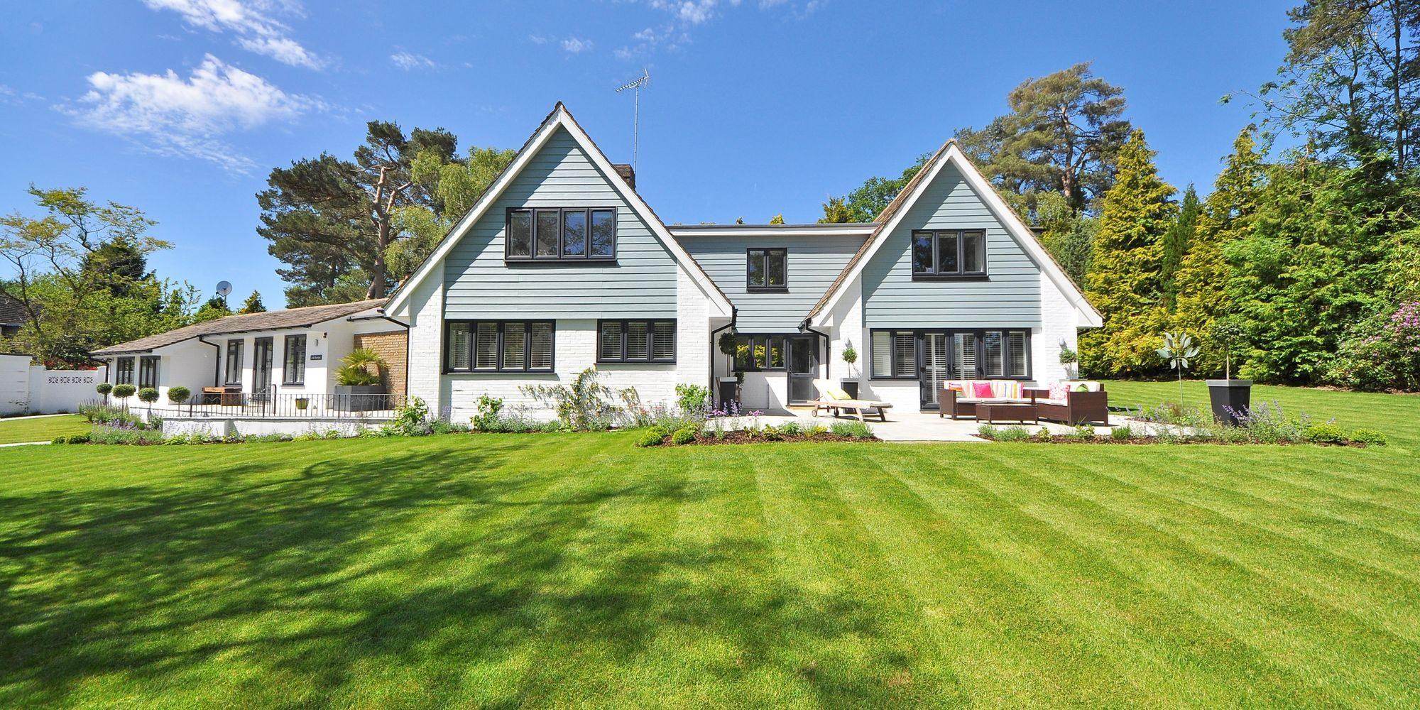 A house behind a large lawn with fresh mowing stripes running across it