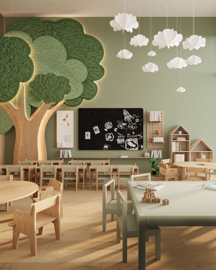 A calm daycare room with small wooden tables and chairs, a leafy tree mural and paper clouds hanging from the ceiling