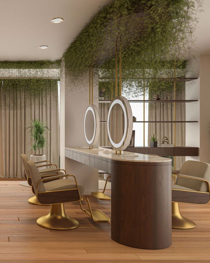 A quiet salon with sand colored styling chairs, round lit mirrors, wood floors and trailing greenery overhead