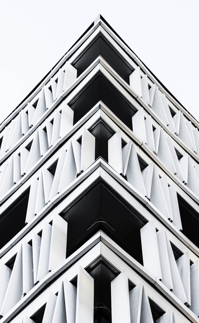 A repeating white concrete facade of stacked chevron balconies, photographed straight on in high contrast.