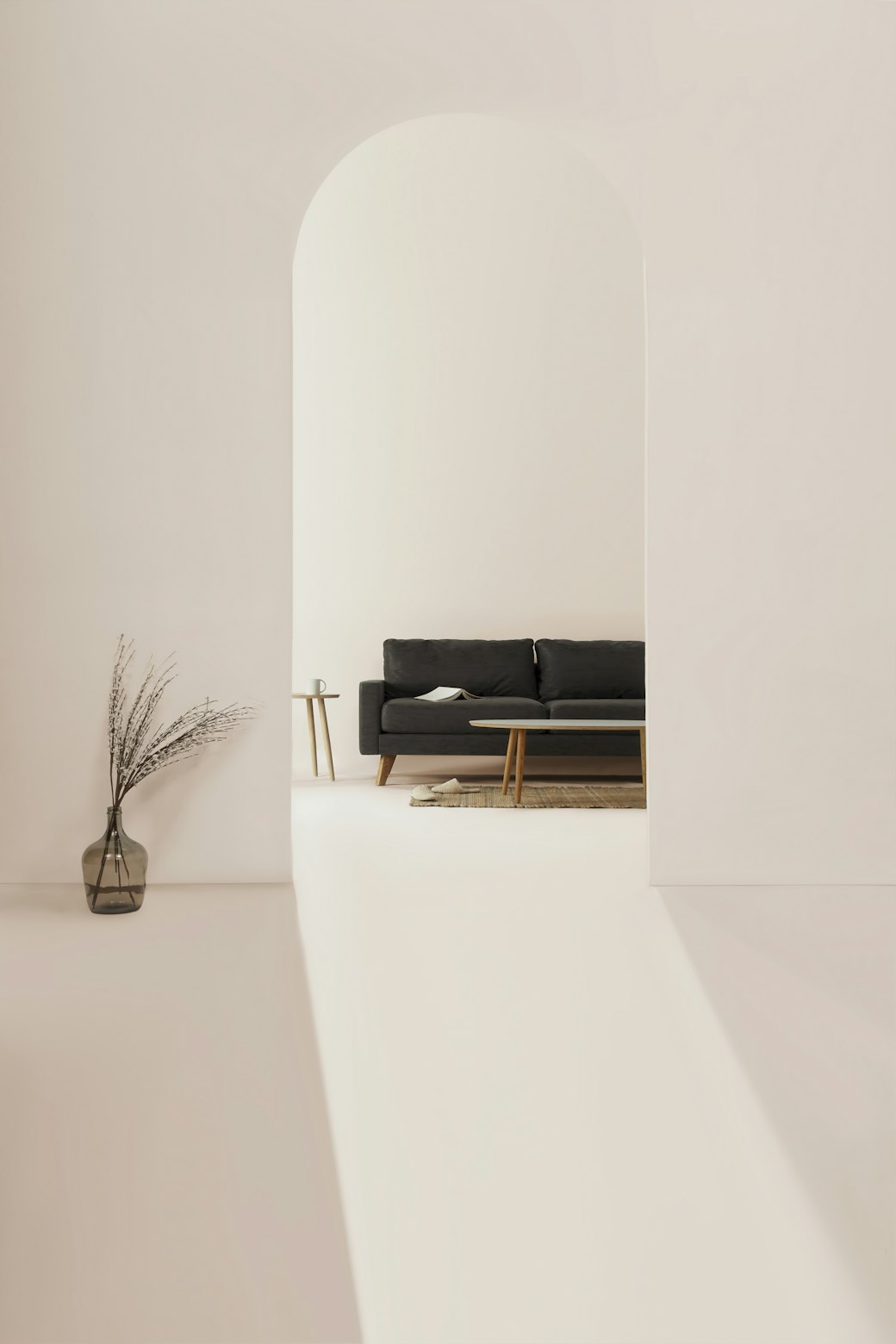 A tall arched alcove in a pale plaster wall, holding a low dark bench and a slim vase of dried stems.