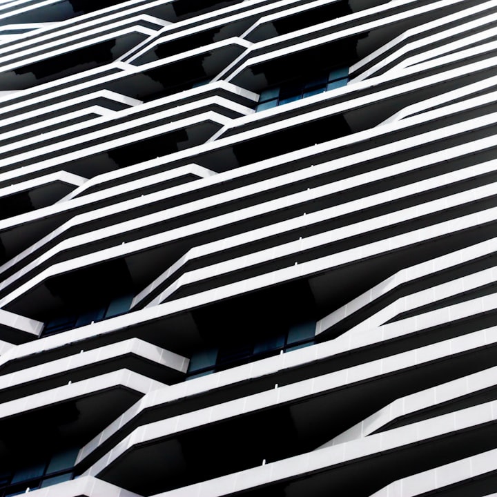 A parking structure facade of alternating white fins and dark voids, photographed at a steep diagonal.