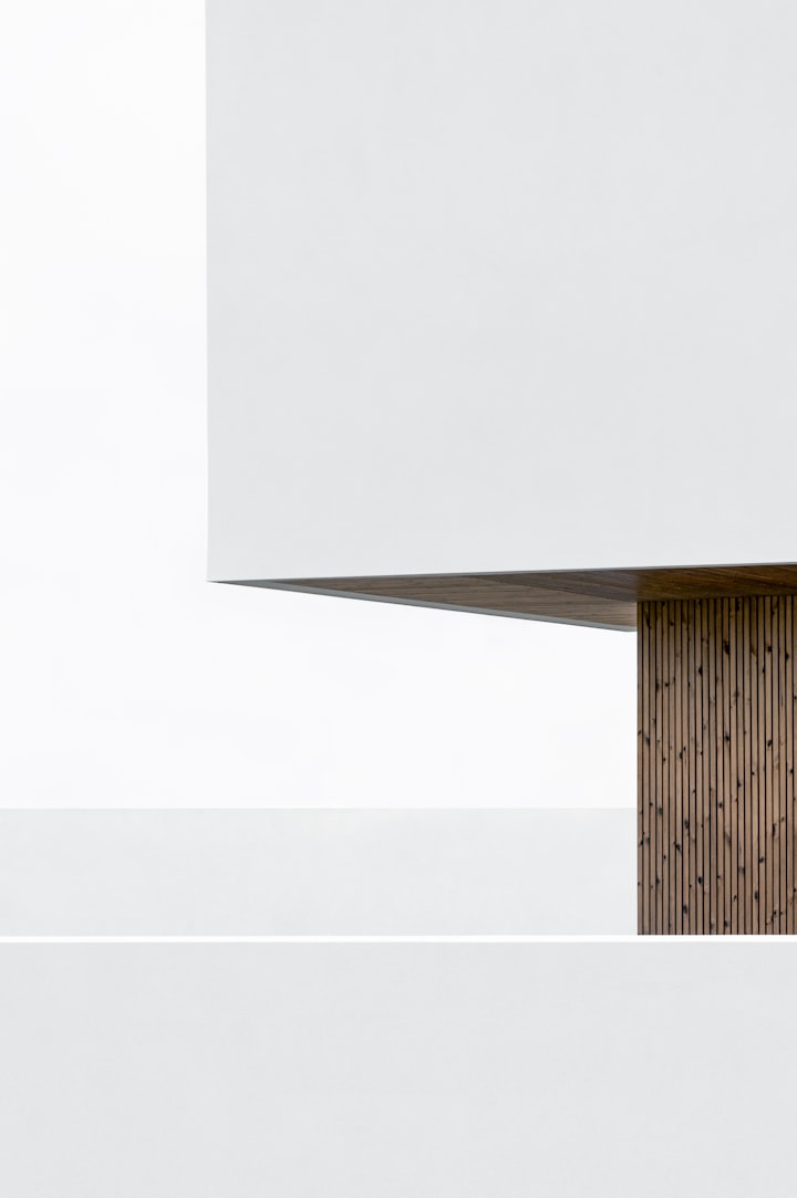 The white underside of a cantilevered canopy meeting a slatted timber soffit against a bright sky.
