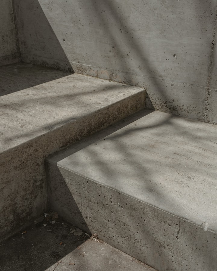 A detail of poured concrete stair treads, raked by hard sunlight that throws a diagonal shadow across the risers.